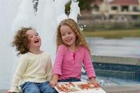Two girls laughing by a fountain.